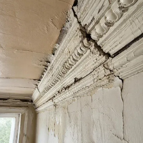 Cracked ornate plaster cornice running along an old ceiling edge