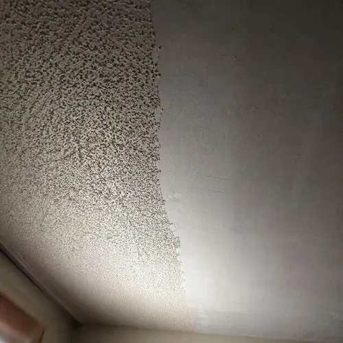 Partially scraped ceiling showing bare drywall where the stipple texture has been removed