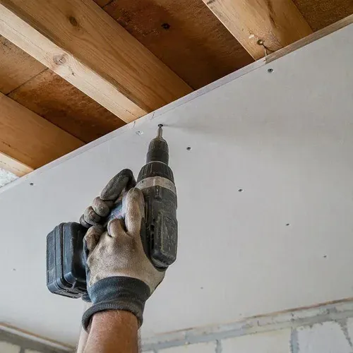 Screwing 5/8 inch drywall to ceiling joists, set flush so no screw pops show through the finish